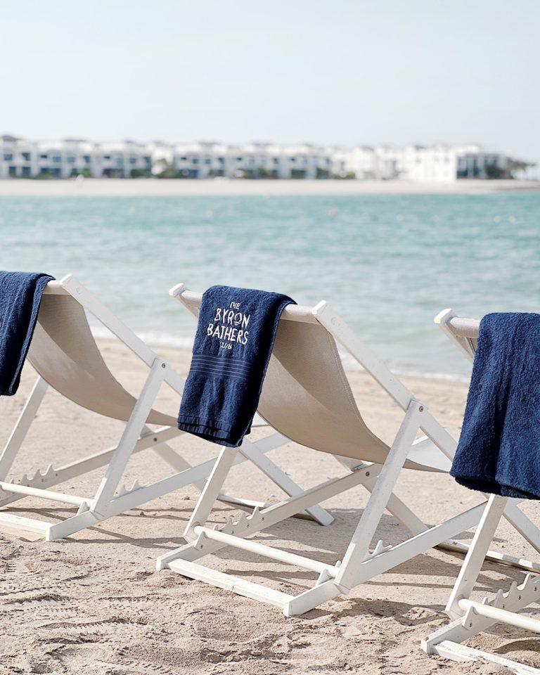 Beach loungers with Byron Bathers towels on the sand