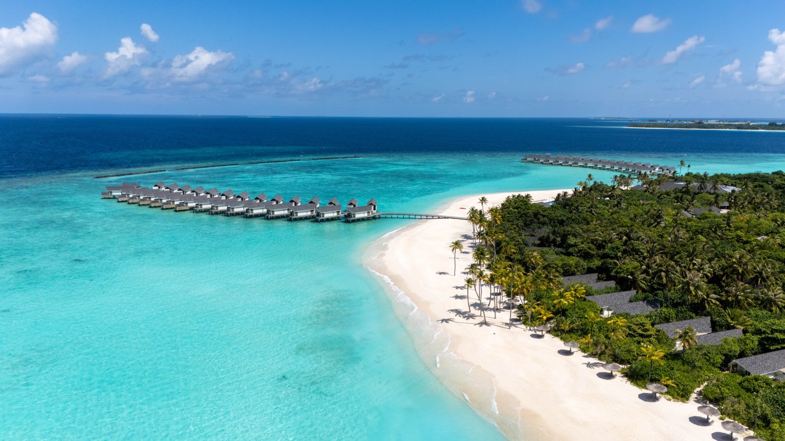 Aerial view of RAAYA by Atmosphere in the Maldives, with overwater villas and a white sand beach