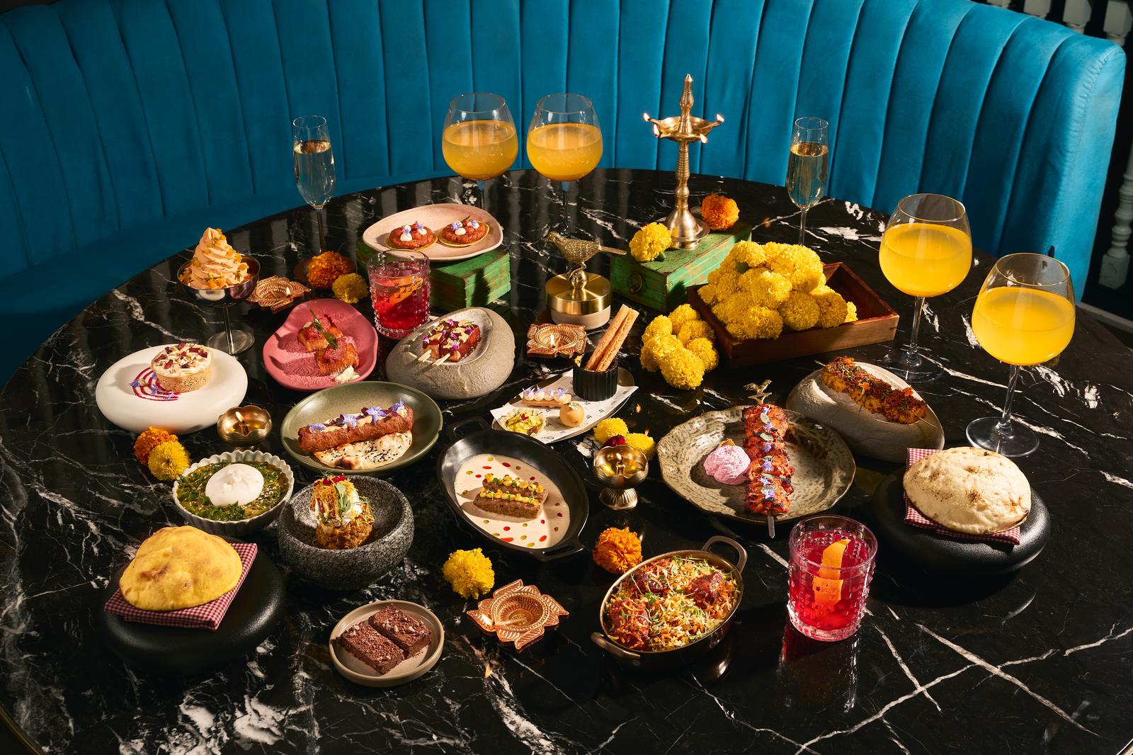 The Diwali tasting menu laid out on a black marble table beside a teal banquette at Bombay Borough in DIFC