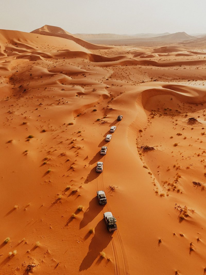 Aerial view of a convoy of 4x4 vehicles crossing sand dunes
