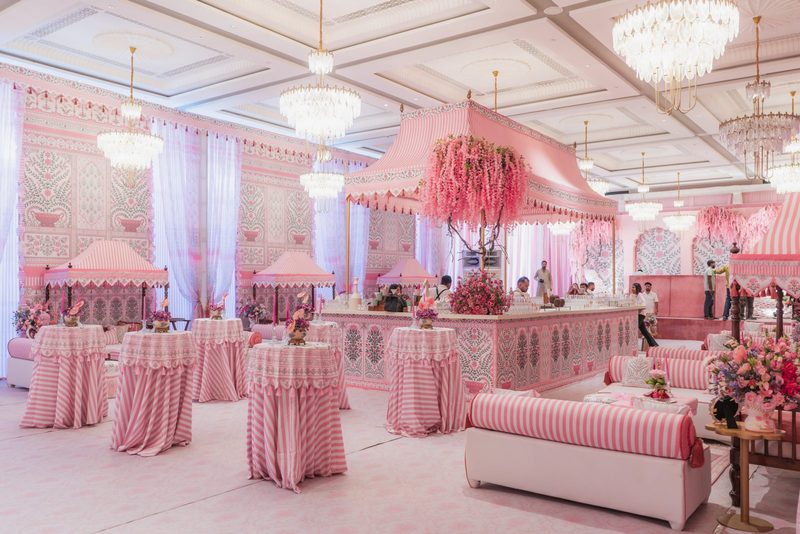 A pink-themed lounge with striped tables, tented bar and chandeliers designed by Envelop