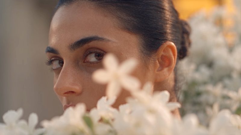 Close-up of a model's face, partly framed by out-of-focus white flowers