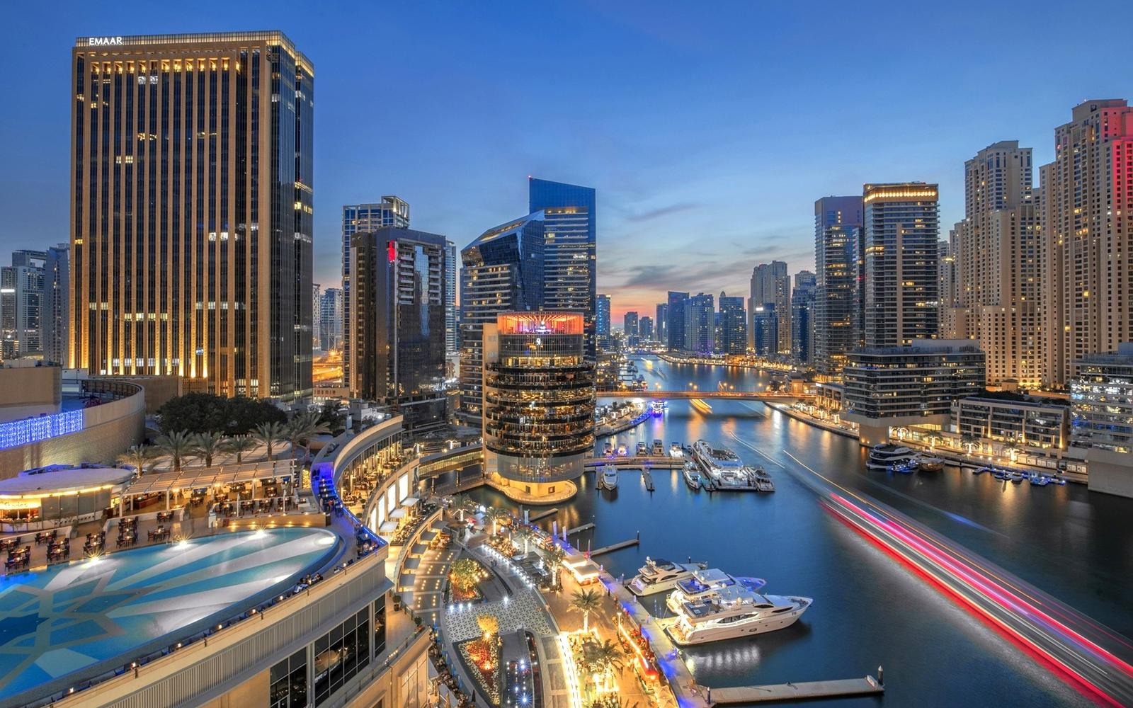 Dubai Marina towers and yachts at dusk with light trails on the water