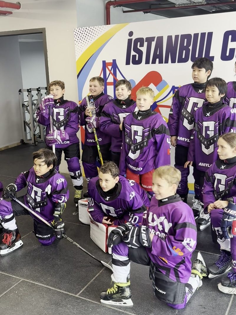 The Galaxy Warriors squad in purple jerseys, some kneeling with sticks and skates, in front of the Istanbul Cup wall