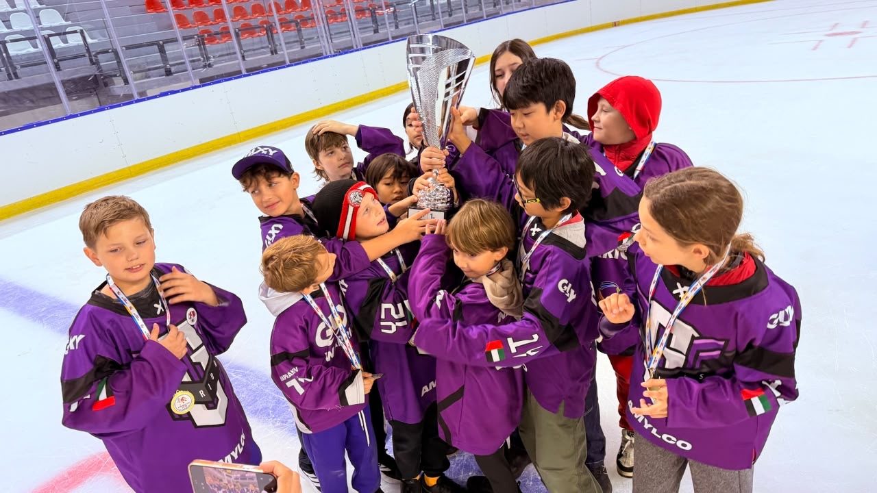 Galaxy Warriors players in purple jerseys, medals around their necks, gather around the Istanbul Cup trophy on the ice