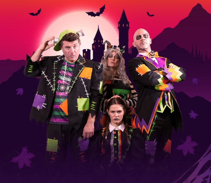 Promotional image for Haunted Timesylvania showing four performers in colourful patchwork Halloween costumes, one with a green cap and bolts at the temples, in front of a purple castle and a large red moon