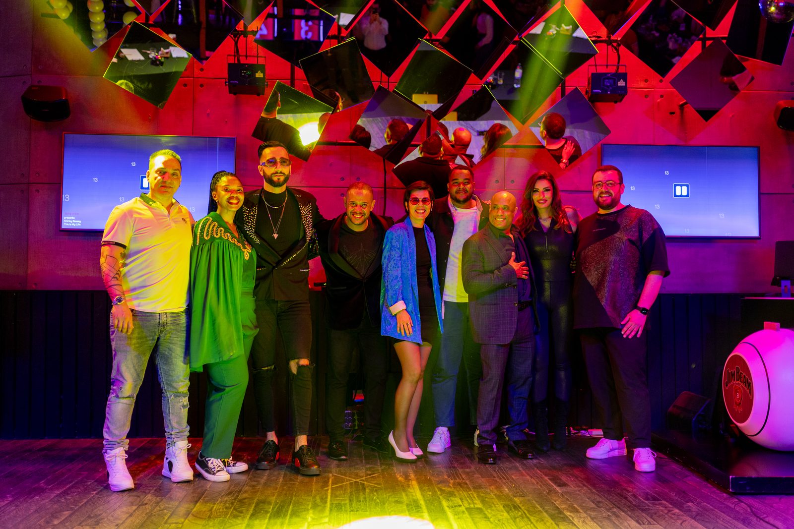 A group of people lined up on the Lucky Voice stage under red lighting and mirrored panels