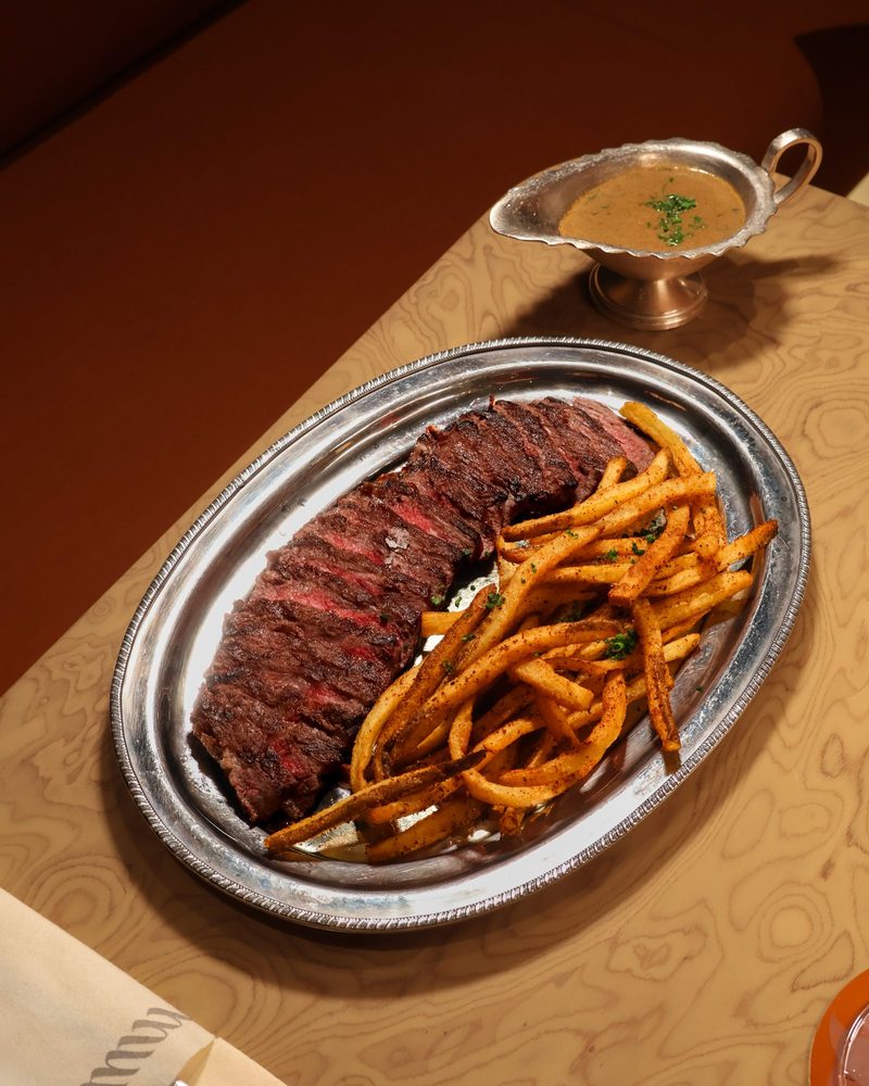 A sliced beef dish with fries on a silver platter at Murmur