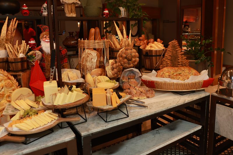 A buffet table stacked with breads, cheeses and festive decorations