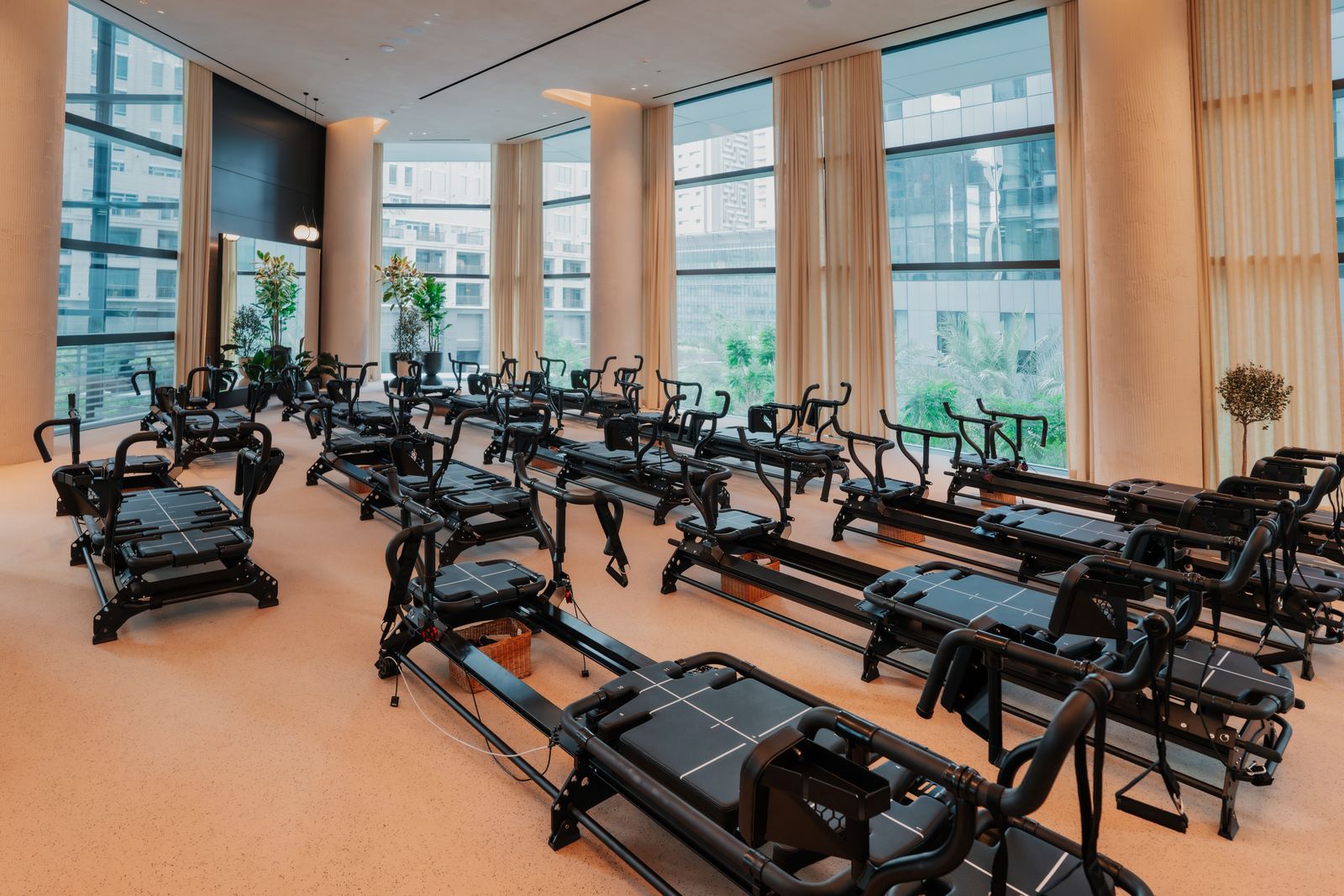 Rows of black reformer machines in the bright main studio at Reform Athletica, ICD Brookfield Place, with tall windows along one side