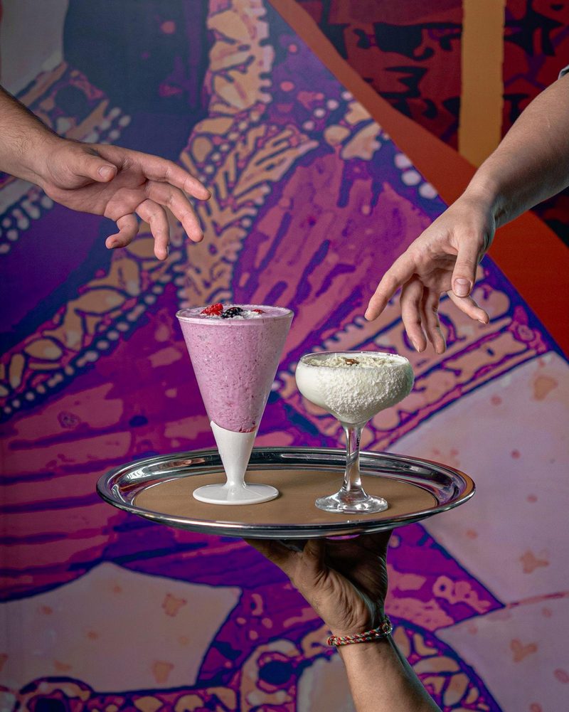 A Very Berry Lassi topped with fresh berries and coconut on a dark marble table