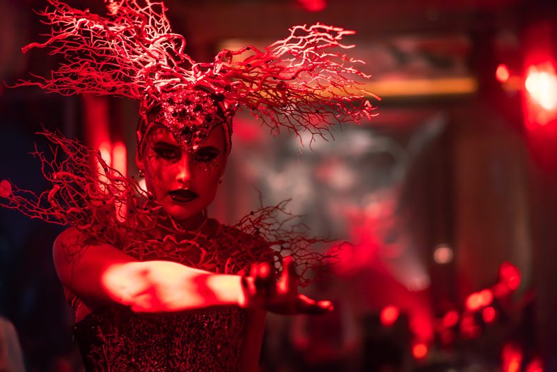 A performer in a red coral-branch headdress at Sexy Fish Dubai