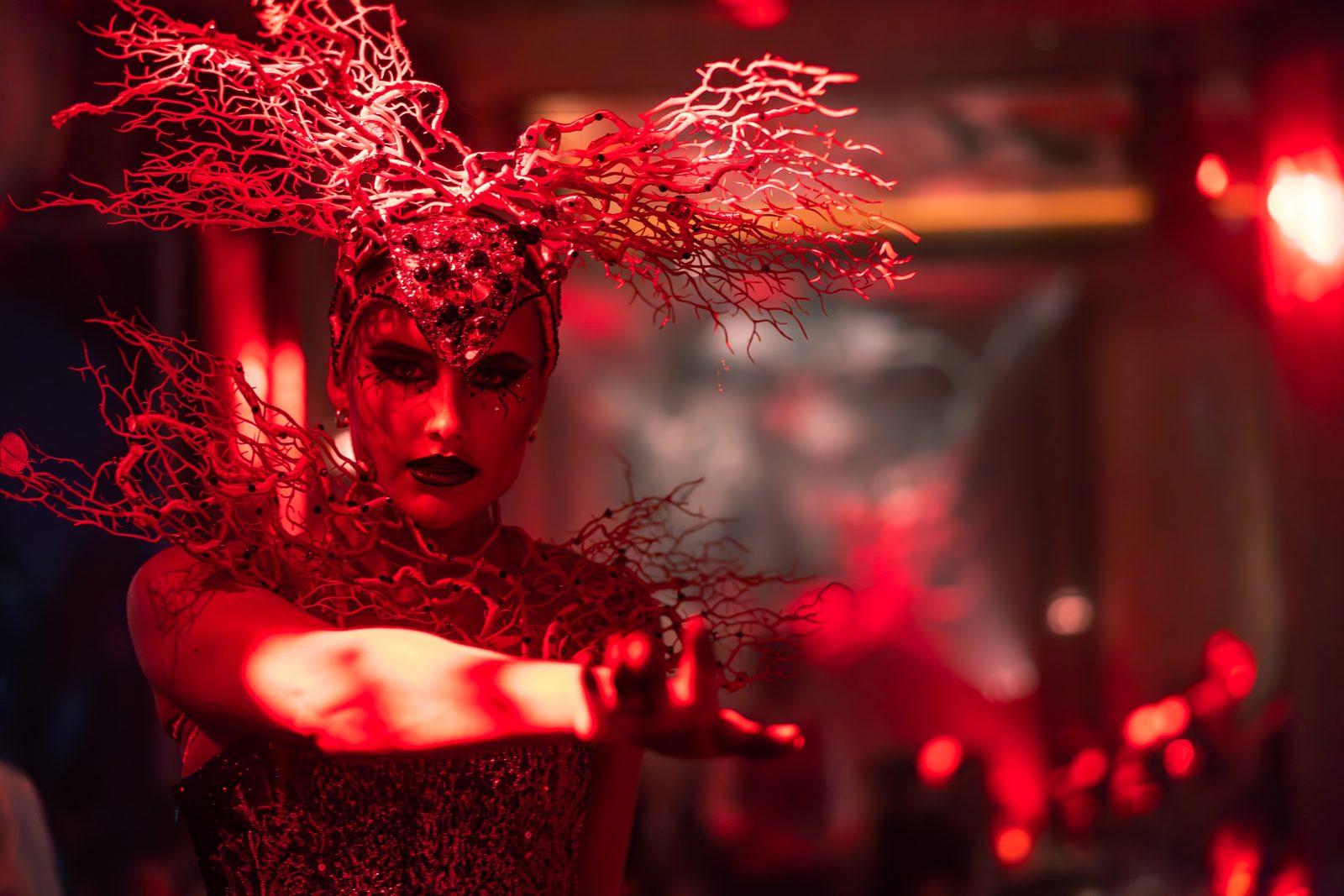 A performer in a red coral-branch headdress at Sexy Fish Dubai
