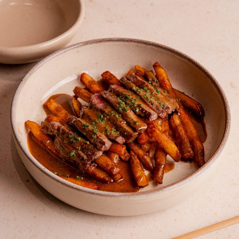 Sliced steak over fries with sauce and chives, SLRP’s Steak 9+ Fries