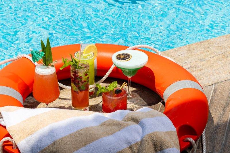 Three drinks served on an orange lifebuoy by the pool