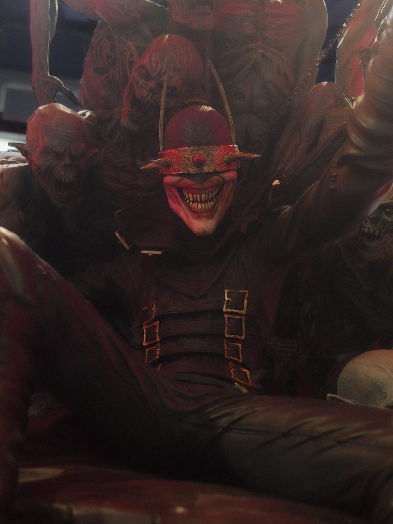 Collectible statue of a grinning masked figure among demonic figures