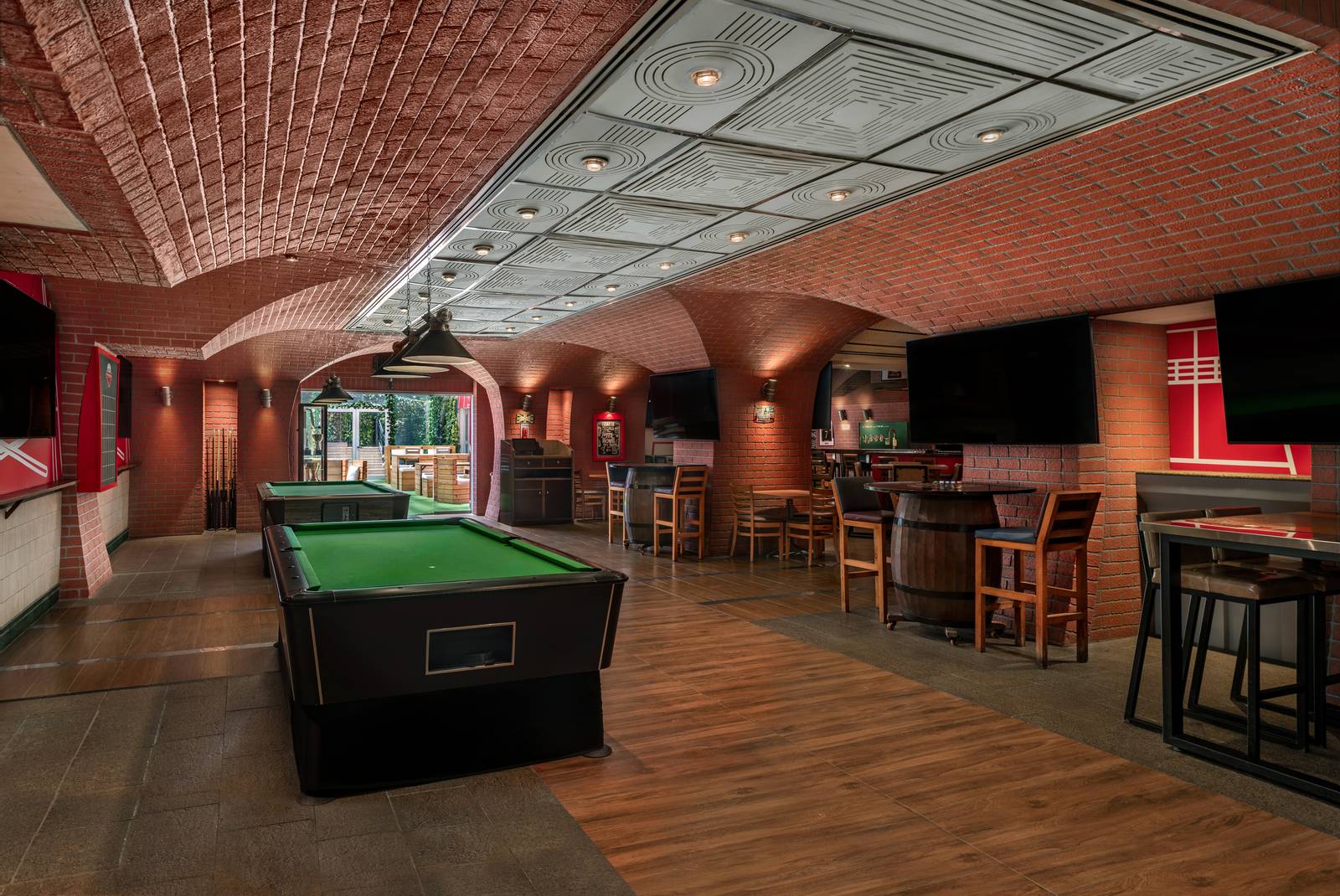 The red brick vaulted interior of The Underground Pub, with a pool table, bar stools and wall-mounted screens