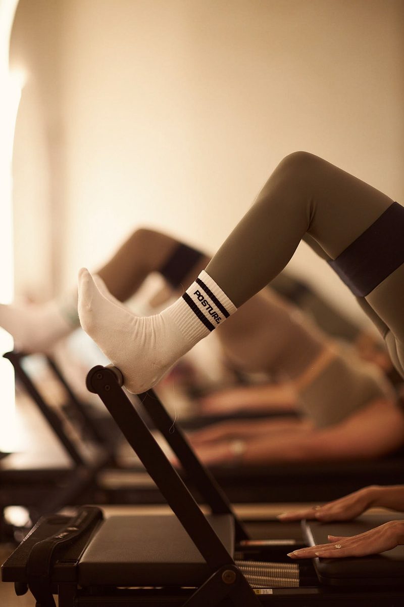 A client in POSTURE socks works on a Pilates reformer