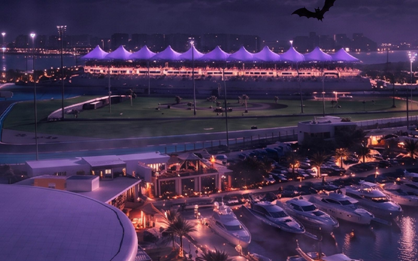 Yas Marina at night with yachts in the harbour, pumpkins along the promenade, bats in a purple sky and a full moon over the circuit grandstand