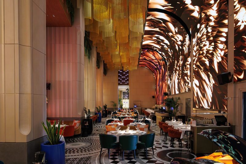 The ZENON dining room at Kempinski Central Avenue, with a gold draped ceiling and curved projection walls