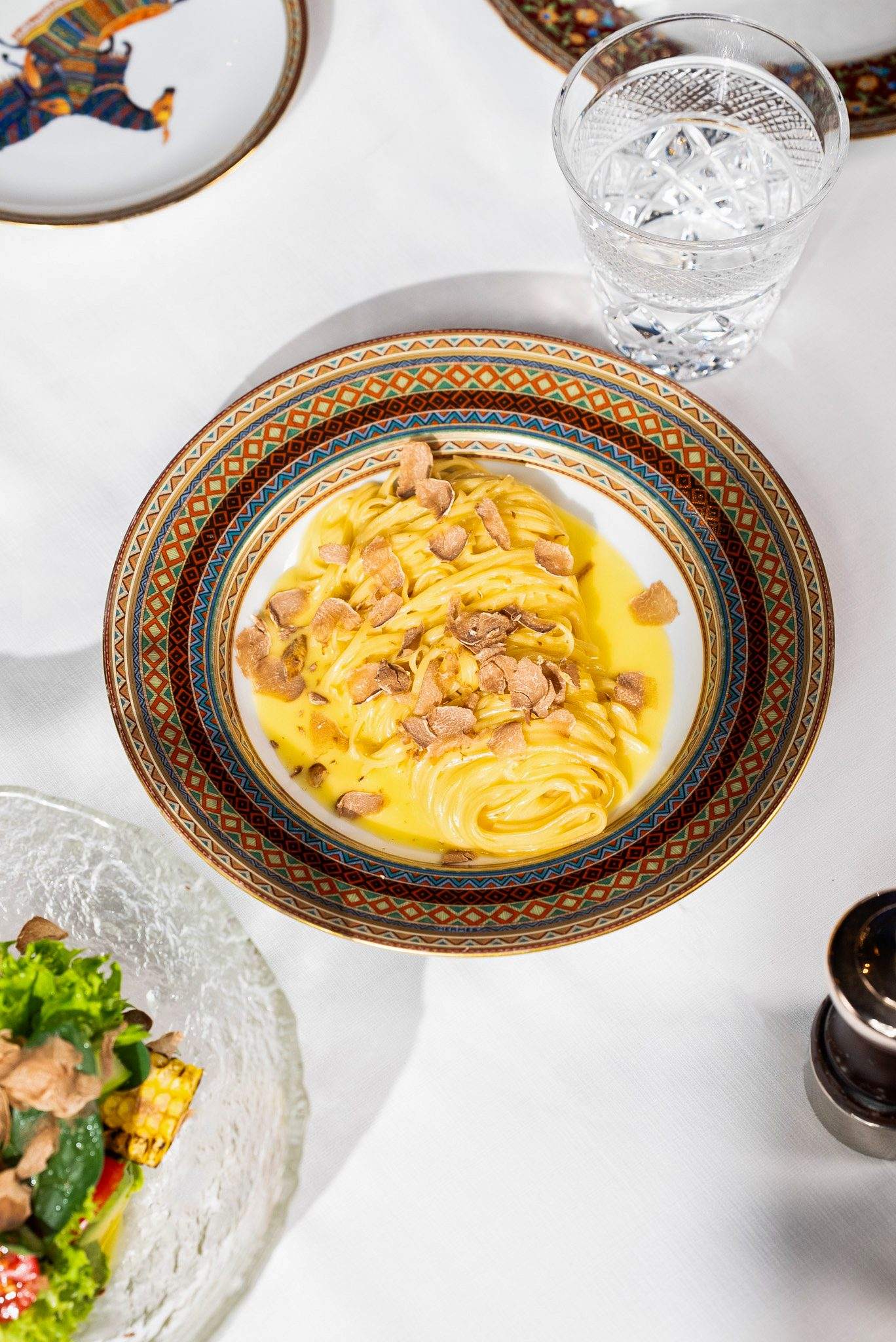 Homemade tagliolini topped with shaved white truffle on a patterned plate at ZENON Dubai